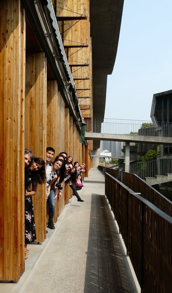 CCA students and faculty, Professor Lisa Findley, peering from behind wooden shutters lining the outer wall of the China Academy of Art