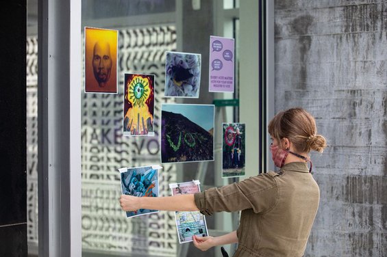 Director of Exhibitions Jaime Austin installs the CCA@CCA Artwork Campaign in the windows of the CCA Hubbell Street Galleries. Photo by Nicholas Lea Bruno.