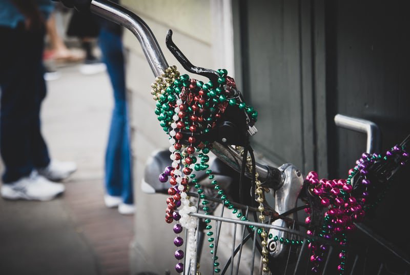 Colorful strands of Mardi Gras beads strung on bike handles