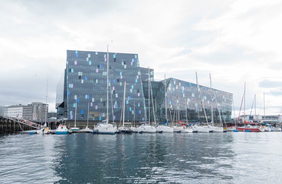 Sailboats lined up in front of the modern Harpa Concert Hall, covered in blocks of iridescent color, shimmering like the sea.